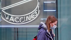 Una mujer con una máscara contra el coronavirus pasa por delante de un cartel de neón en el Instituto Wellcome de Londres, el martes 2 de febrero de 2021. 