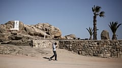 رجل يتحدث في هاتفه الجوال وخلفه نصب تذكاري للإبادة الجماعية التي يقال إن القوات الألمانية ارتكبتها ضد شعب هيريرو وناما في عام 1904 في معسكر اعتقال سابق بجزيرة القرش بناميبيا