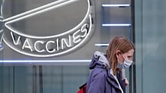 Eine Frau mit Maske läuft an einem Neon-Schriftzug des Wellcome Institutes vorbei, 02.02.2021