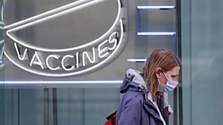Eine Frau mit Maske läuft an einem Neon-Schriftzug des Wellcome Institutes vorbei, 02.02.2021