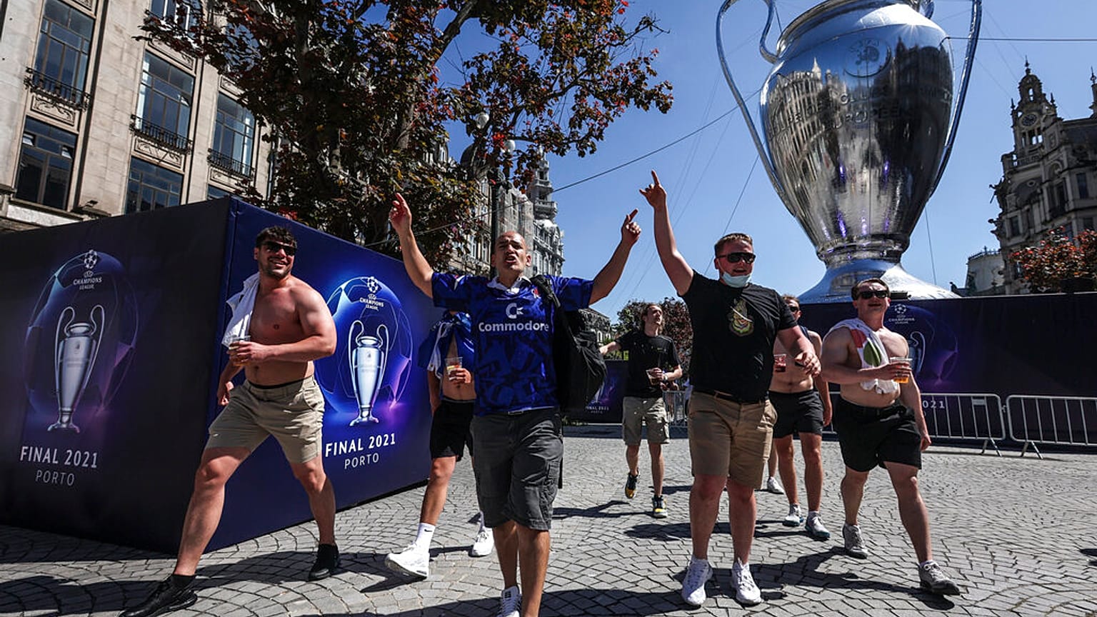 Chelsea supporters walk past a giant replica of the Champions League trophy in downtown Porto