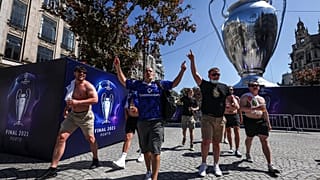 Chelsea supporters walk past a giant replica of the Champions League trophy in downtown Porto