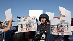 صحفي يحمل لافتة تدين الانتهاكات بحق الصحفيين الفلسطينين في حي الشيخ جراح، القدس.