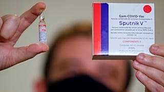 Egy brazil gyógyszertári dolgozó felmutatja a Szputnyik V vakcinát