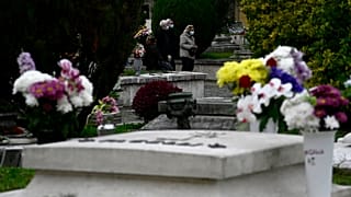 أشخاص يضعون على وجوههم كمامات للوقاية من كورونا يسيرون بالقرب من القبور في مقبرة فيرانو بالعاصمة الإيطالية روما
