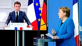 French President Emmanuel Macron is seen on a video screen during a joint press conference with German Chancellor Angela Merkel
