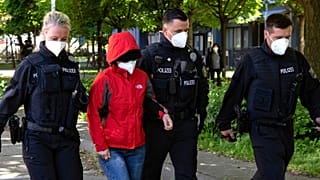 Police officers lead a woman to a vehicle during a raid in Berlin against people suspected of smuggling Vietnamese people in Europe May 31, 2021