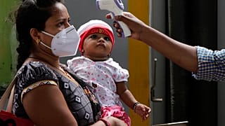 Un sanitario toma la temperatura a una mujer en Bombay, India