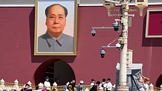 With surveillance cameras seen on a pole, plainclothes security personnel watch as tourists visits Tiananmen Gate on the 32nd anniversary of a deadly crackdown on protest.