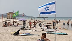 Tavaly májusi fotó: emberek napoznak és sétálnak egy tengerparti strandon Tel-Avivban