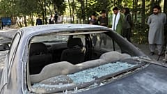 Afghan men look at a damage car after a roadside bomb explosion in Kabul, Afghanistan, Sunday, June 6, 2021.