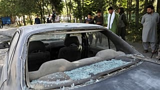 Afghan men look at a damage car after a roadside bomb explosion in Kabul, Afghanistan, Sunday, June 6, 2021.