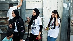 In this Friday, June 4, 2021 photo, Palestinian activist Muna el-Kurd, centre, wears a medal from a marathon as she leaves the site where Israeli police fired tear gas.
