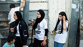 In this Friday, June 4, 2021 photo, Palestinian activist Muna el-Kurd, centre, wears a medal from a marathon as she leaves the site where Israeli police fired tear gas.