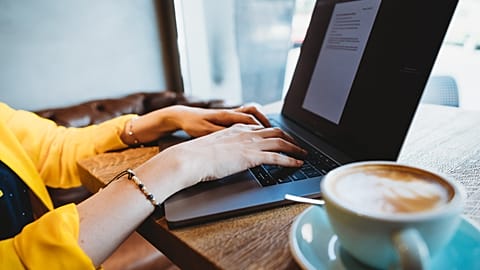 Digital nomad works on a laptop in a café.