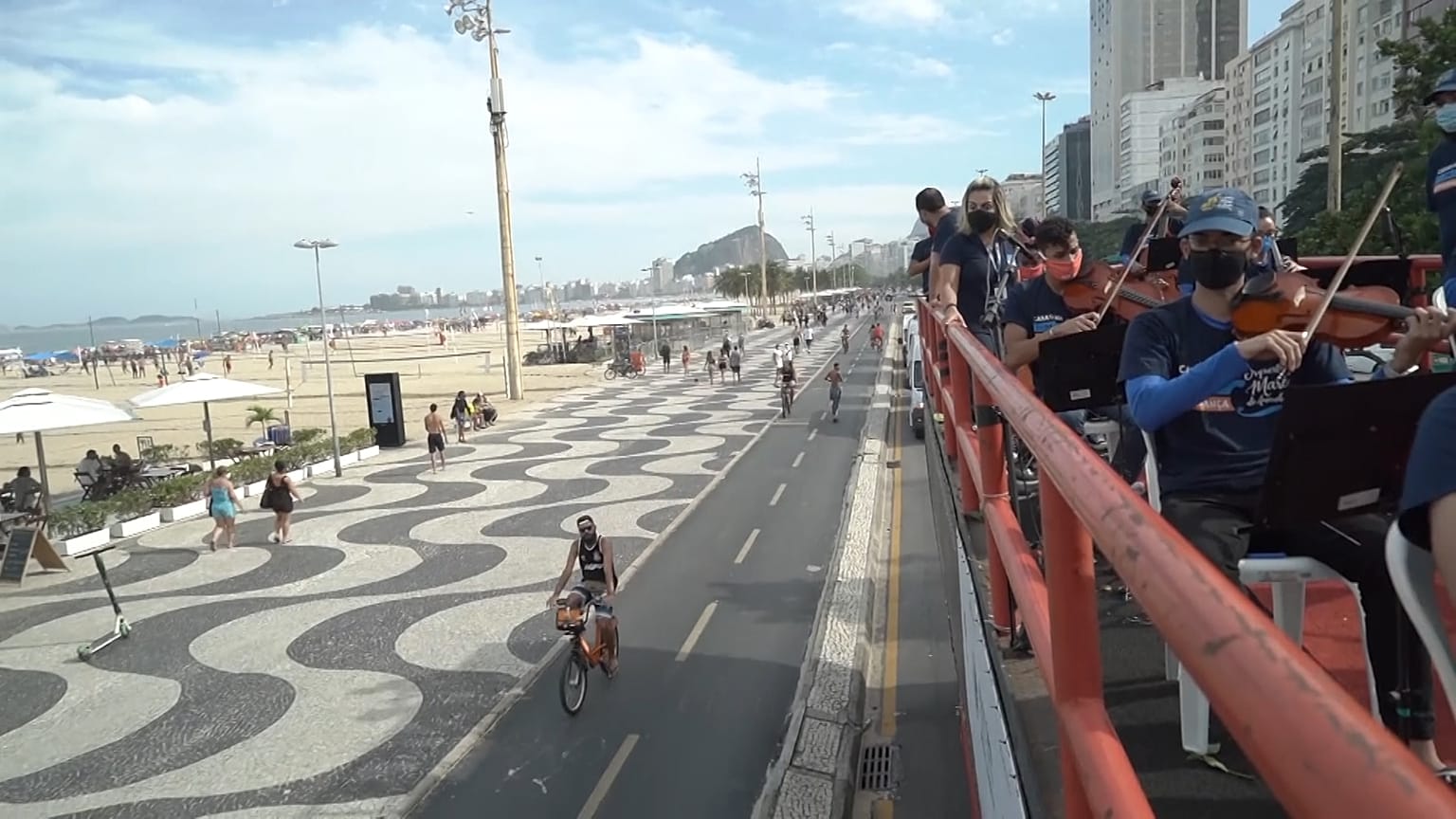 Musicians playing violins and other classical instruments on top of a truck next to Copacabana beach