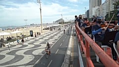 Musicians playing violins and other classical instruments on top of a truck next to Copacabana beach
