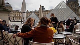 People drink outdoors on a bar terrace in front of the Louvre museum in Paris, Thursday, May 20, 2021. 
