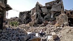 FILE: In this Saturday, July 27, 2019 photo, a man rides his motorcycle through the rubble of the old city of Aleppo, Syria. 