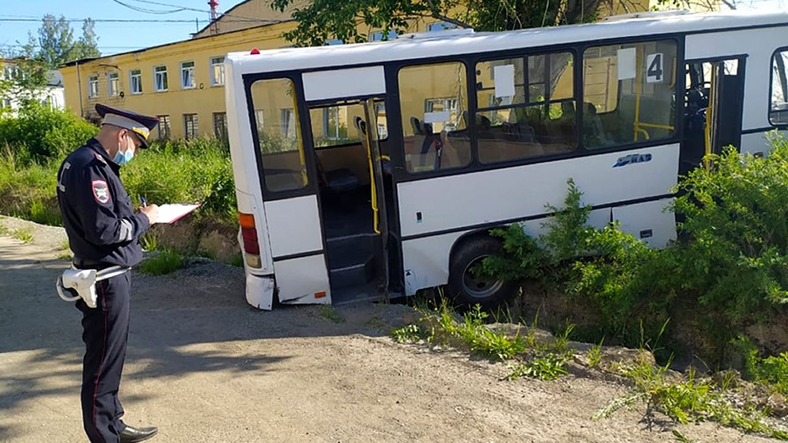 A Russian police officer stands near the damaged bus.