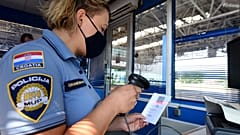 Horvát határőr szkenneli a Covid-igazolvány kódját a horvát-szlovén határon