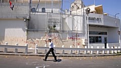 Un policía camina frente a la embajada estadounidense dañada después de que manifestantes progubernamentales atacaran la embajada en Damasco