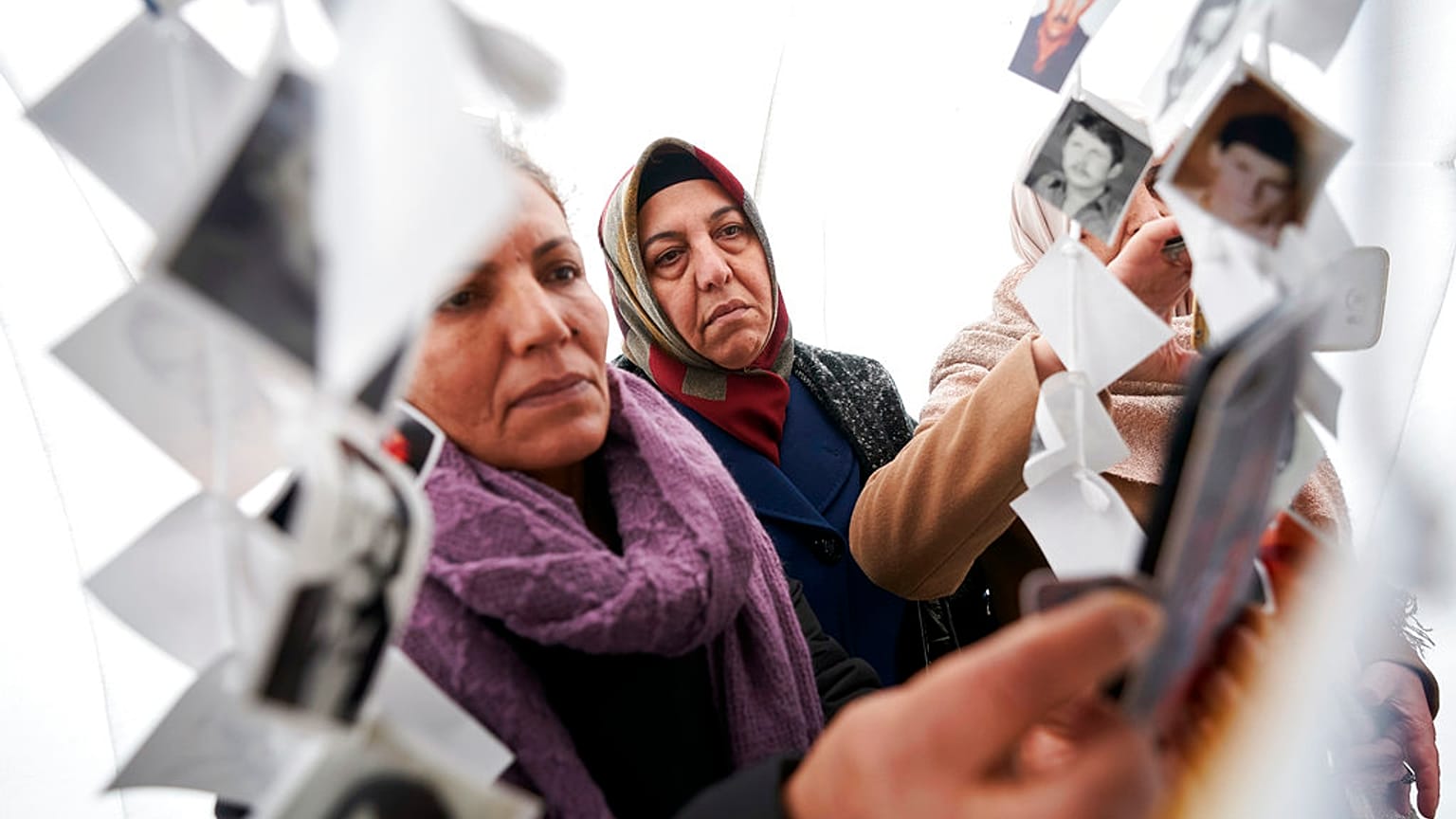 Women look at images of victims inside a traveling monument called 'Prijedor 92' outside the Yugoslav War Crimes Tribunal, ICTY