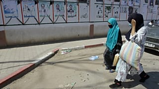 جزائريات يسرن بجانب ملصقات دعائية انتخابية