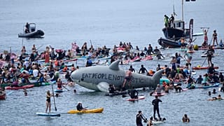 Paddleboarders and surfers take part in a paddle out to raise awareness for climate action in the sea at Gyllyngvase Beach in Falmouth, Cornwall, England, June 12, 2021.