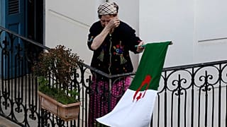 امرأة تمسح دموعها وهي تحمل العلم الوطني مع خروج المتظاهرين إلى الشوارع في العاصمة الجزائرية لرفض الانتخابات الرئاسية ، الجزائر، 27 ديسمبر 2019