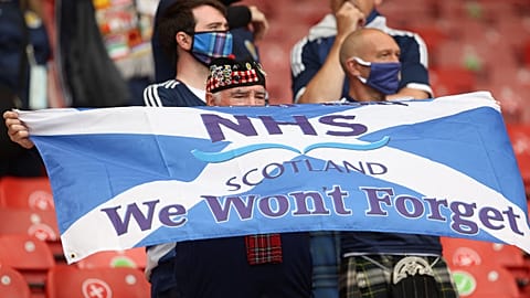 A Scotland supporter holds a Scottish flag with a message in support of the NHS.