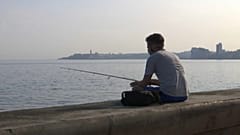 Un joven pesca con caña en el Malecón de La Habana