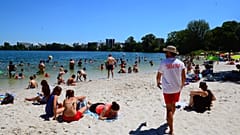 People gather on a sunny afternoon as rescuer walks on the beach of the Lake of Bordeaux, south-western France.