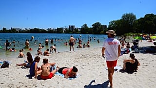 People gather on a sunny afternoon as rescuer walks on the beach of the Lake of Bordeaux, south-western France.