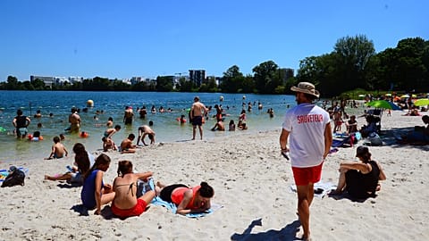 People gather on a sunny afternoon as rescuer walks on the beach of the Lake of Bordeaux, south-western France.