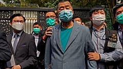 FILE - In this April 18, 2020, file photo, Jimmy Lai, center, who founded newspaper Apple Daily, is arrested by police officers at his home in Hong Kong. 