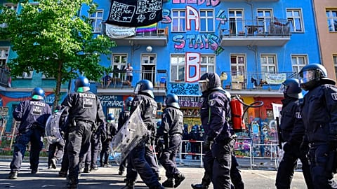 People stand on a balcony as police prepares to enter a building in Rigaer Strasse street in Berlin.