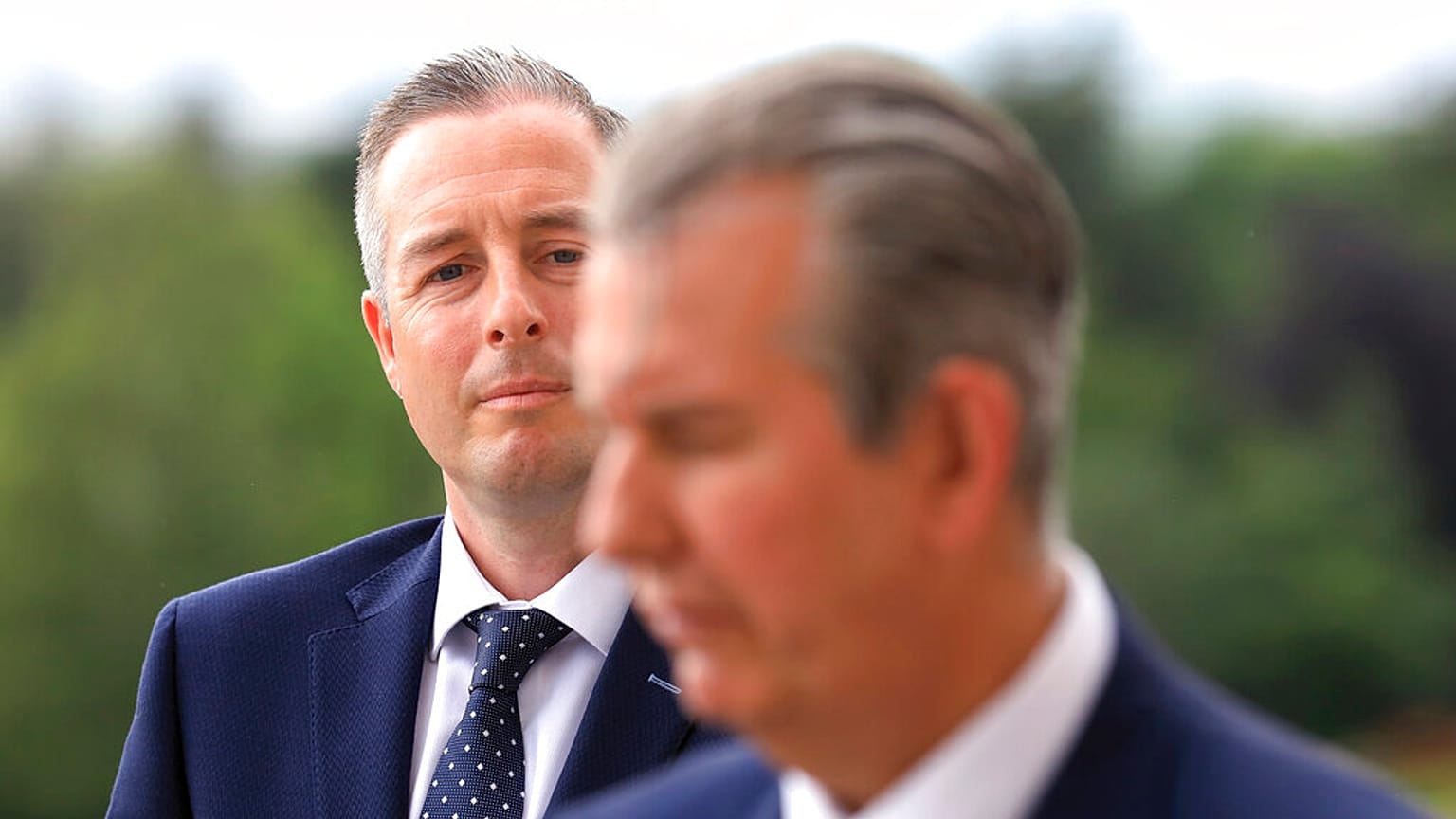 In this Tuesday, June 8, 2021 file photo, Democratic Unionist Party member Paul Givan, background, looks at party leader Edwin Poots during a press conference at Stormont.