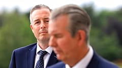 In this Tuesday, June 8, 2021 file photo, Democratic Unionist Party member Paul Givan, background, looks at party leader Edwin Poots during a press conference at Stormont.