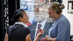 Deux femmes échangent à Erevan, devant une affiche de campagne, le 16 juin 2021, Arménie