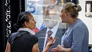 Deux femmes échangent à Erevan, devant une affiche de campagne, le 16 juin 2021, Arménie