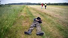 Two participants of an illegal rave party cross a field and one lies, in Redon, north-western France, on June 19, 2021, as French gendarmes intervene to disperse the event