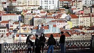 FILE - In this March 11, 2021 file photo, a group of young people wearing face masks chat at a viewpoint overlooking Lisbon's old center. 