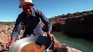 منقب للماس يغسل الحصى الذي أخذه من مجرى يمر عبر منجم نوبل دايموند في روستنبرج، جنوب إفريقيا.