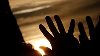 People raise their hands meditating during the summer solstice