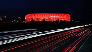FILE - In this Monday, March 16, 2020 file photo, cars pass the illuminated 'Allianz Arena' soccer stadium in Munich, Germany.