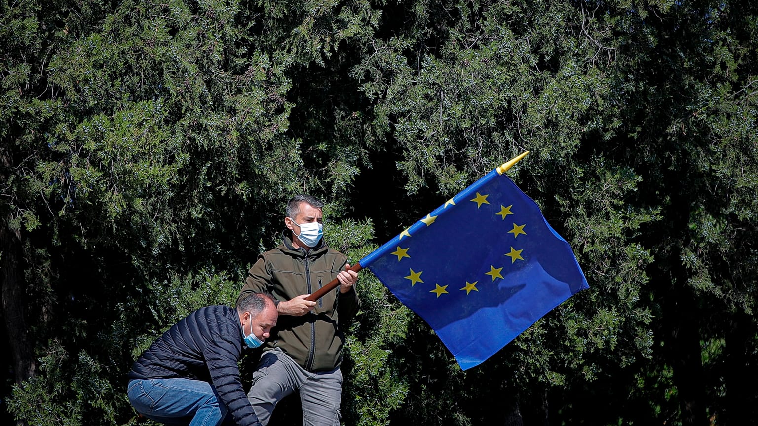 A man removes an European Union flag at the end of ceremonies marking the 76th anniversary of the end of World War II in Europe and Europe Day, in Bucharest, Romania, Sunday, 