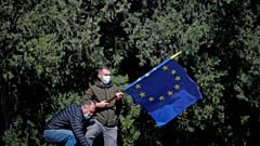 A man removes an European Union flag at the end of ceremonies marking the 76th anniversary of the end of World War II in Europe and Europe Day, in Bucharest, Romania, Sunday, 