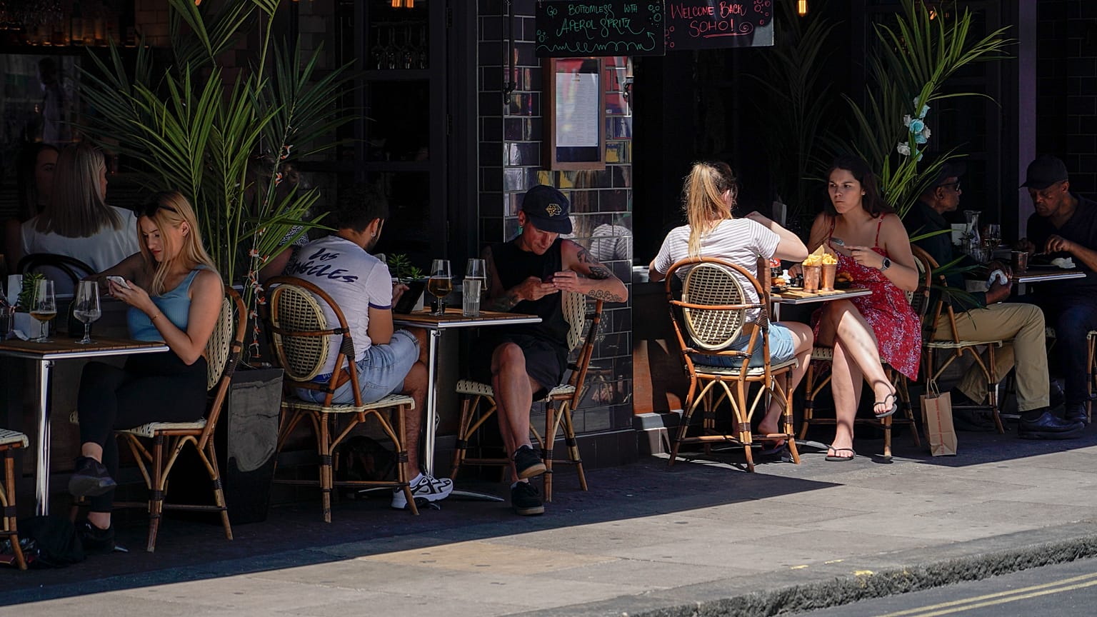 Personas sentadas en mesas al aire libre en un restaurante en el Soho, en Londres, el lunes 14 de junio de 2021.