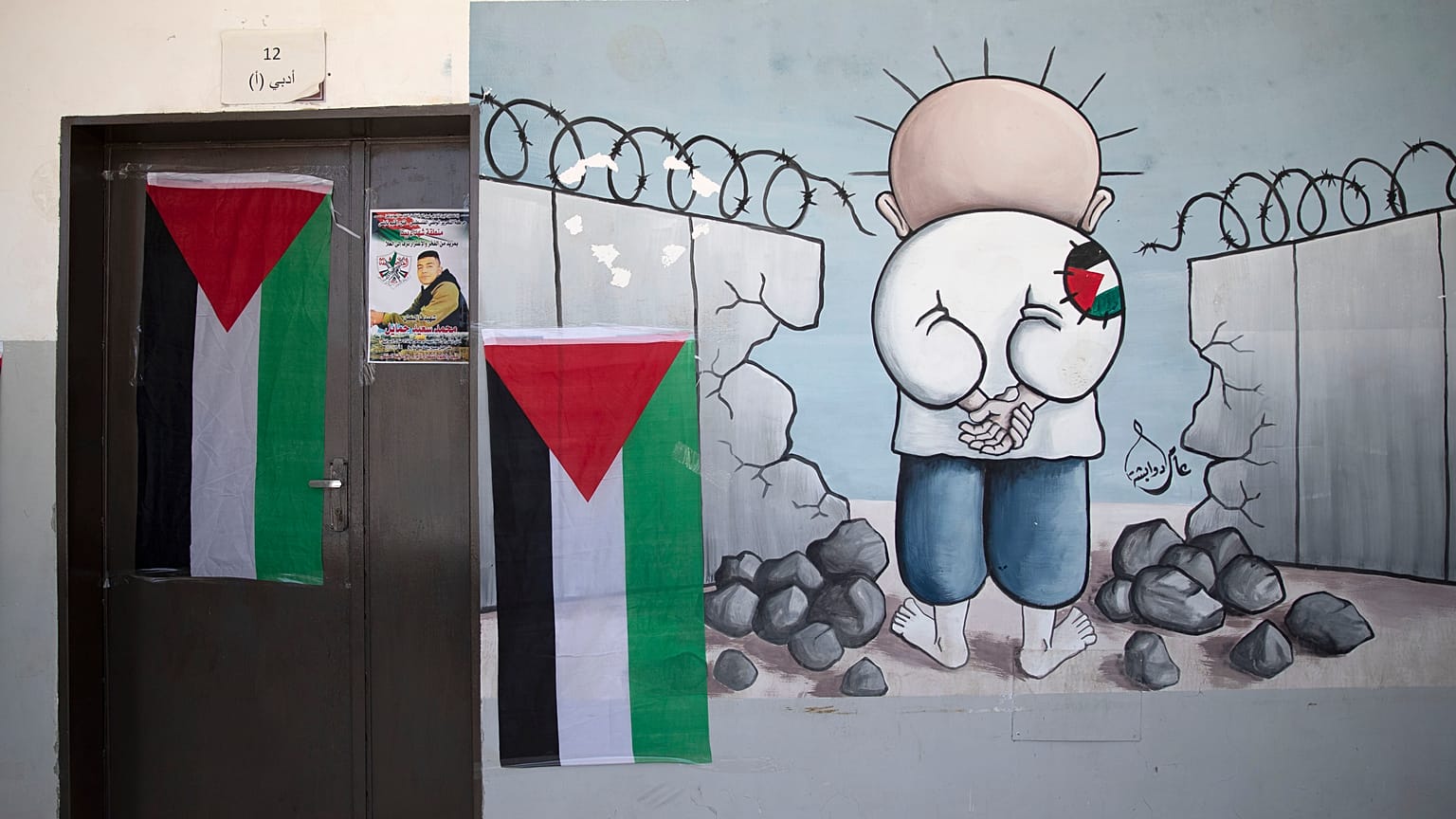 معلقة كاريكاتور للطفل الفلسطيني محمد حمايل توشح باب قسم مدرسي من بلدة بيتا في الضفة الغربية المحتلة. 